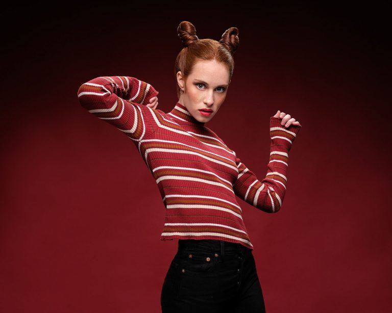 Fotografia de moda del test modelo para Anna Bermejo con moñetes y jersey rojo a rayas estirando los brazos, por el fotografo Juan Segovia en el estudio de Punt de Vista