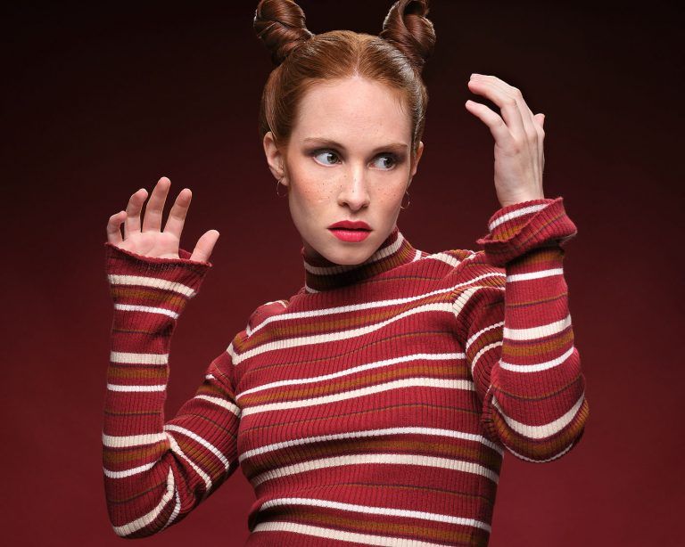 Fotografia de moda del test modelo para Anna Bermejo con moñetes y jersey rojo a rayas levantando las manos, por el fotografo Juan Segovia en el estudio de Punt de Vista