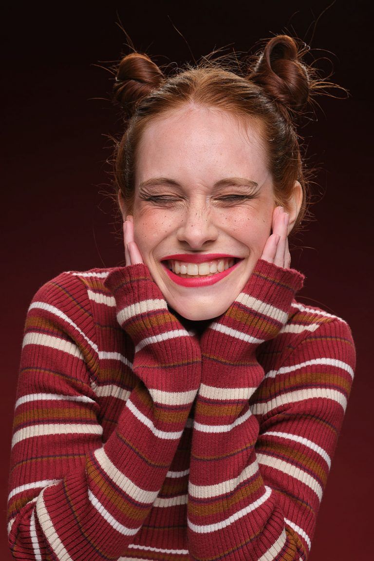 Fotografia de moda del test modelo para Anna Bermejo con moñetes y jersey rojo a rayas sonriendo con los ojos cerrados, por el fotografo Juan Segovia en el estudio de Punt de Vista
