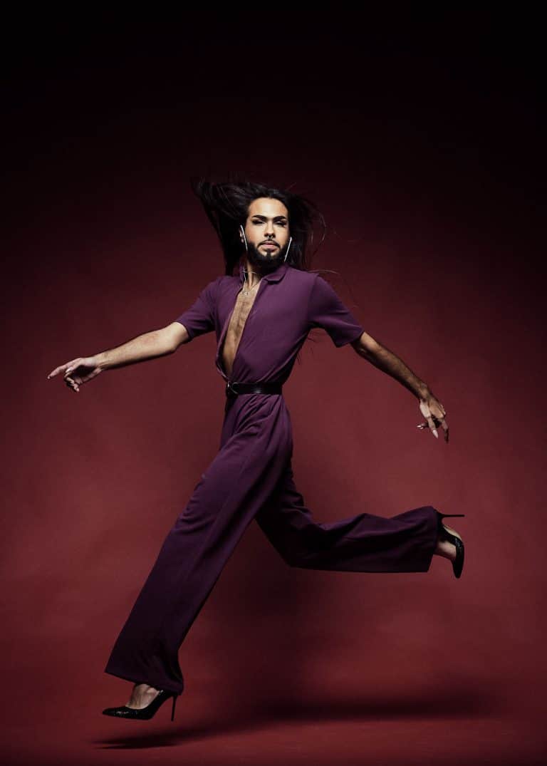 Fotografia de moda con el modelo David Molina saltando con su mono lila y sus zapatos de tacon sobre fondo granate por el fotografo Juan Segovia en el estudio fotografico de Punt de Vista