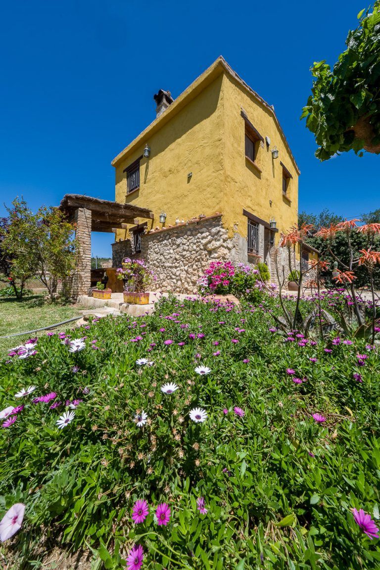 Fotografia de flores y casa en la casa rural Lo maset de Carmeta en Tivenys, Tarragona