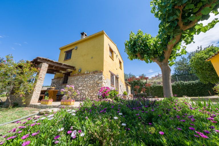 Fotografia del jardin con edificio de la casa rural Lo maset de Carmeta en Tivenys, Tarragona