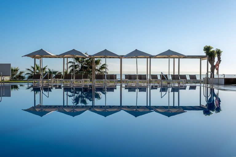 Sombrillas y hamacas reflejadas en la piscina del hotel Torrequebrada en Málaga